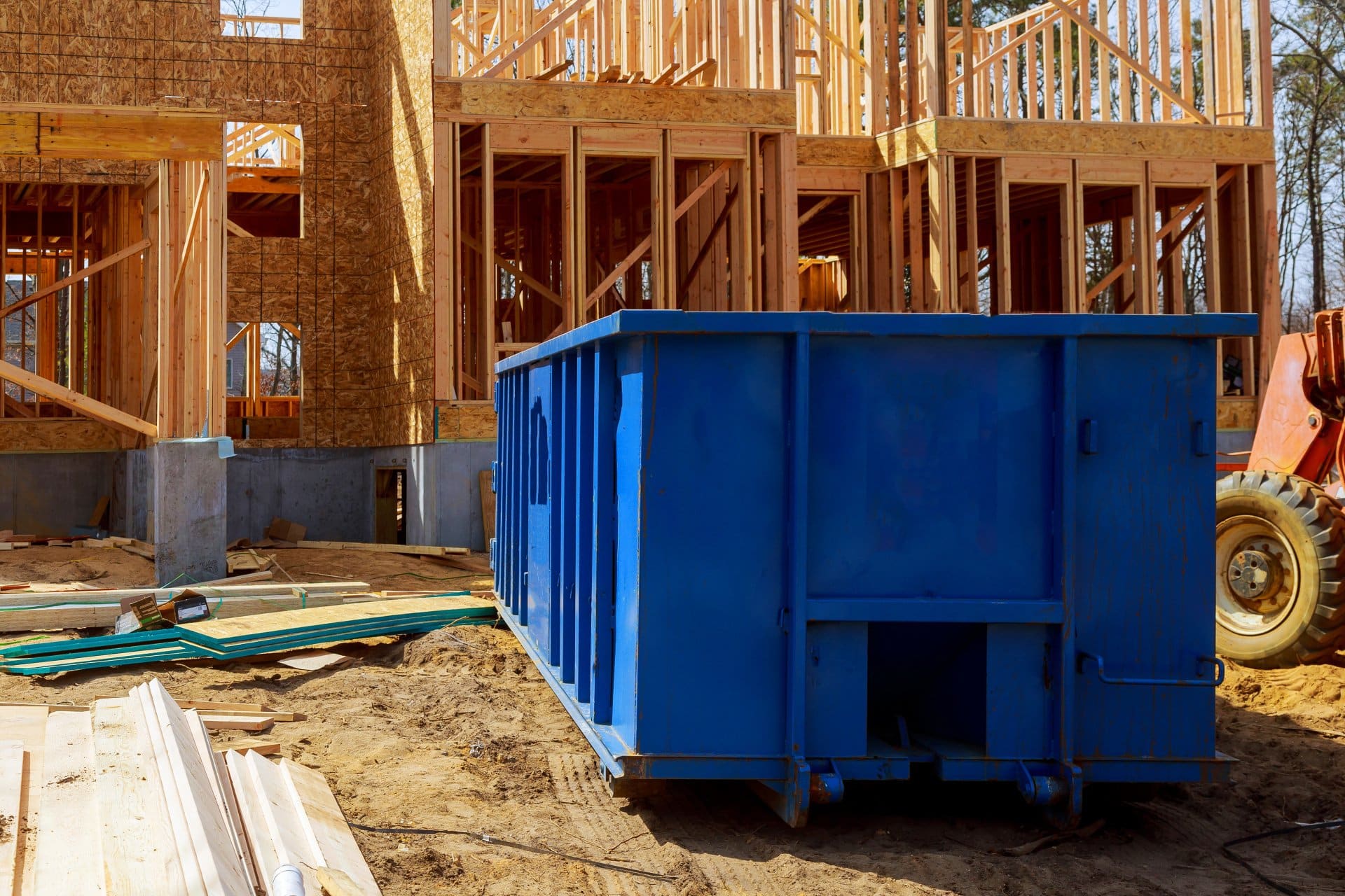 A photo of a home renovation project in progress with a blue dumpster on the jobsite.