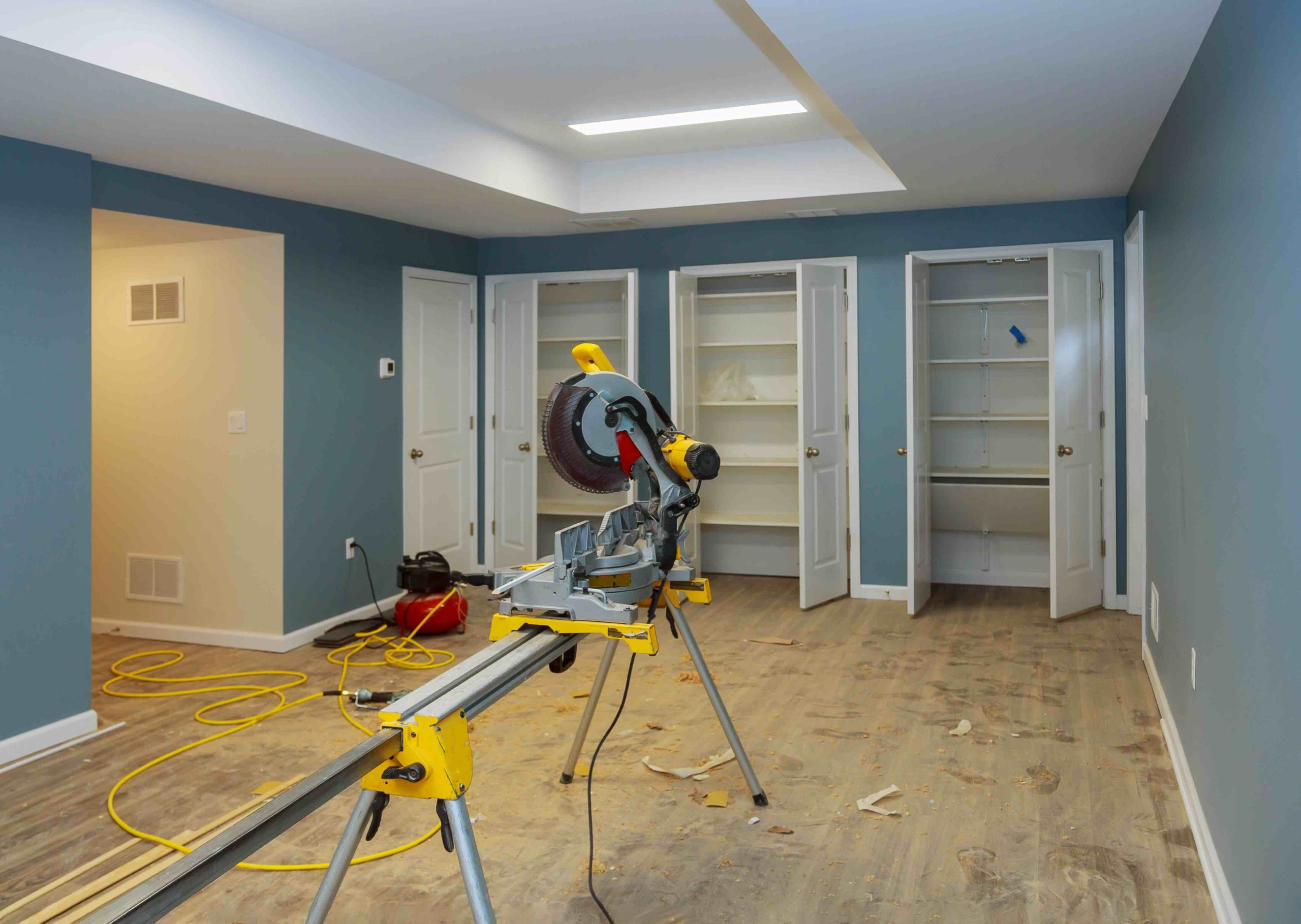 A photo of an ongoing basement remodel project, with a a saw and equipment positioned in the middle of the room.